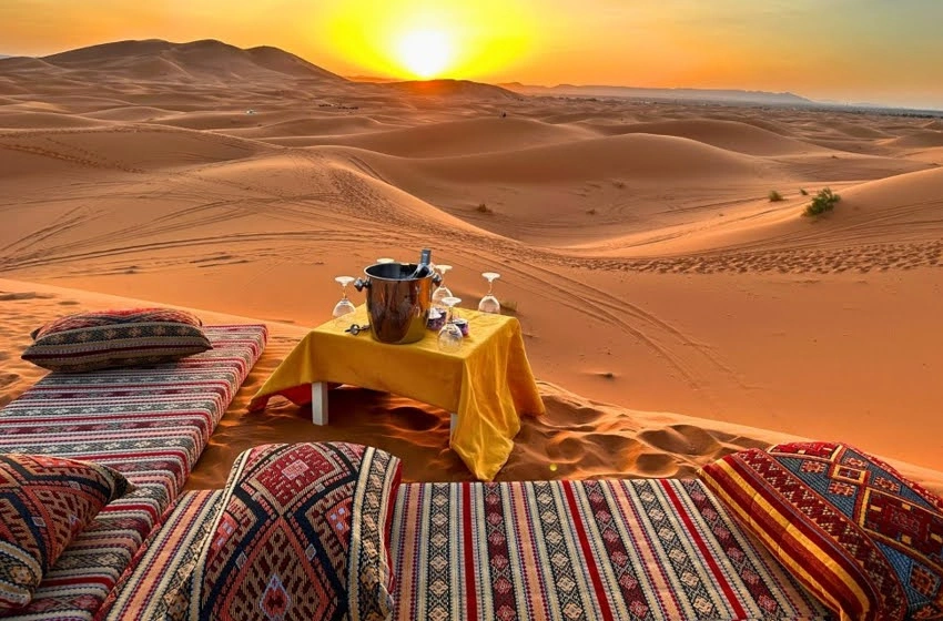 Table dressée pour un dîner dans le désert au coucher du soleil